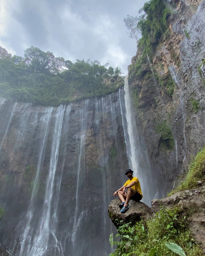 Sitting on a rock in front of a waterfall in Indonesia